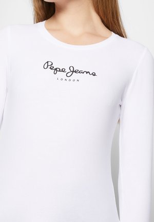Vrouw draagt een wit shirt met lange mouwen met het "Pepe Jeans London"-logo in het zwart op de borst gedrukt.
