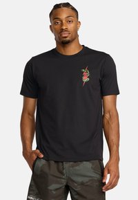 Zwart katoenen T-shirt met een groen en rood slanglogo op de linkerborst. Korte mouwen en een ronde halslijn. Glad textuur.