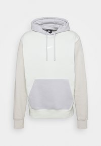 Sudadera con capucha de color gris claro y crema, con un bolsillo delantero, puños elásticos y un sutil logo de Nike en el pecho. Textura suave y diseño casual.