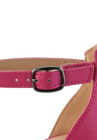 Rosa Kunstleder-Fesselriemen mit einer metallischen Schnalle, der über Nähdetails und eine glatte Textur verfügt. Das Innere hat einen neutralen Farbton.