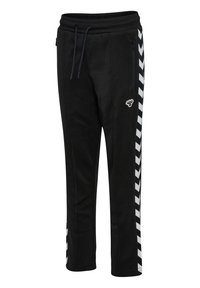 Zwarte sweaterbroek met elastische tailleband, trekkoord en zijzakken. Witte chevronpatroon langs de zijkanten. Zachte textuur.