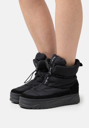 Botas negras hasta el tobillo con una parte superior de textil acolchado, acentos de ante, cordón ajustable y una suela de goma gruesa y texturizada.