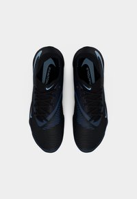 Μαύρα αθλητικά παπούτσια με μπλε λεπτομέρειες, υφή στην επάνω επιφάνεια και κορδόνια. Διαθέτουν αεροδυναμικό σχεδιασμό με ορατή επωνυμία και ριγωτό μοτίβο στα πλευρά.