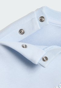 Πολό γιακάς από ανοιχτό γαλάζιο βαμβάκι με κουμπώματα τύπου κλιπ. Διαθέτει πλεκτή υφή και διακριτική ραφή.