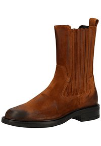 Bottine en daim brun avec panneaux élastiques sur les côtés, bout arrondi et semelle en caoutchouc noir lisse. Détails texturés sur la tige.