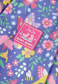 Impermeabile con un motivo floreale blu che presenta accenti rosa, gialli e verdi. Include una patch con logo rosa con la scritta "JoJo splish splash."