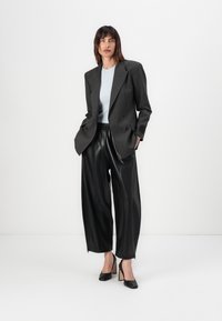 Gestreepte dubbelgeknoopte blazer in donkergrijs, lichtgewicht, gecombineerd met zwarte faux leren wijde broek en zwarte hoge hakken.