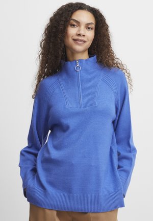 Pull bleu avec un col montant, détail à demi zip, accents côtelés et coupe décontractée. Fabriqué dans une texture lisse et douce.