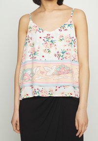 Květinová blůza z lehkého materiálu, s výstřihem do V, tenkými ramínky a pastelovým vzorem s růžovými a modrými akcenty.