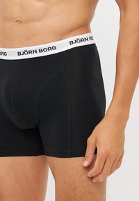 Black boxer briefs with a white elastic waistband featuring "BJÖRN BORG" logo. Smooth fabric, fitted design, and a contoured pouch.