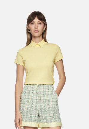 Yellow polo shirt with a collar, paired with light green checkered shorts featuring a textured pattern and cuffed hem.