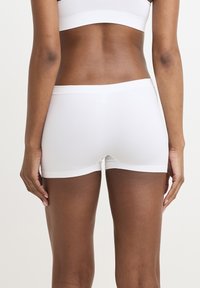 Vita bomullskalsonger för pojkar med en slät yta, med ett brett elastiskt midjeband utan synlig märkning eller mönster.