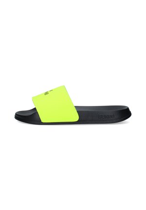 Sandalo tipo slide nero con una larga fascia giallo neon con testo nero e suola texturizzata, mostrato di lato.