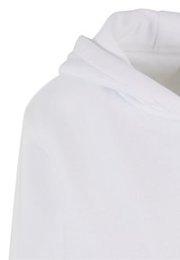 Felpa bianca con cappuccio, caratterizzata da una consistenza morbida, un cappuccio a doppio strato e una vestibilità rilassata. Il tessuto appare liscio con dettagli di cucitura minimi.