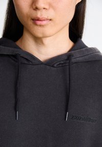 Black hoodie featuring a drawstring, made of soft fabric. Displays a subtle logo on the chest in matching black embroidery.