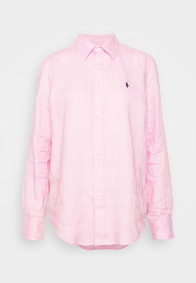 Camisa de linho rosa claro com mangas longas, gola com botões e um pequeno logótipo da polo azul no lado esquerdo do peito. Apresenta um corte descontraído.