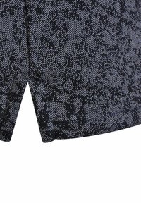 Schwarz-weiße, gemusterte Stoffshorts mit einer strukturierten Optik und einem offenen Nahtdetail am Saum.