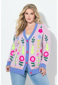 Sweter kardigan w pastelowym różu z głębokim niebieskim kołnierzem i listwą na guziki. Przód zdobią wyhaftowane kwiatowe wzory w jaskrawych kolorach.