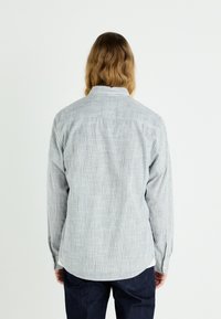 Striped long-sleeve shirt in light blue and white cotton, featuring a classic collar, button cuffs, and a rounded hem. Back view presented.