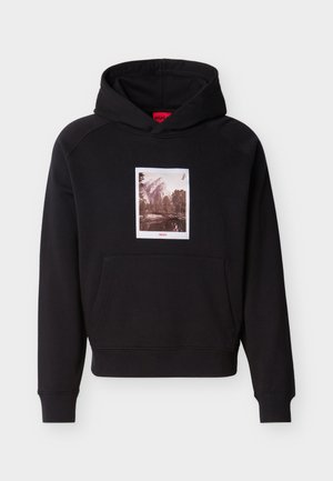 Zwarte hoodie met voorzak en een sepia grafiek van bergen en bomen, gecentreerd boven de zak, met rode "HUGO" tekst.