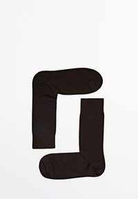 Czarne skarpetki wykonane z miękkiego, elastycznego materiału. Mają zaokrąglony czubek i ściągacz z prążków, ułożone w nachodzącym kształcie L.