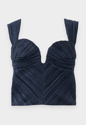 Navy blue pleated crop top with sweetheart neckline and wide straps; features vertical textured lines creating a chevron pattern.