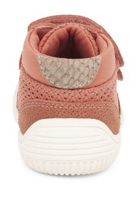 Vista posteriore di un sneaker rosa con una parte superiore in mesh testurizzato, dettagli lisci e una suola in gomma bianca con scanalature orizzontali.