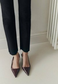 Burgundské lodi�čky na podpatku s špičatou špičkou a designem imitace krokodýla; nošené s černými zkrácenými kalhotami s roztrhanými lemy.