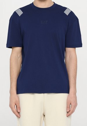 Granatowy bawełniany T-shirt z okrągłym dekoltem i krótkimi rękawami, ozdobiony białymi paskami na ramionach oraz subtelnym logo na piersi.