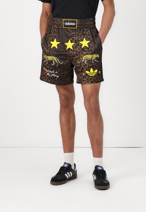 Løveprint shorts med gule stjerner, broderede leoparder og Adidas-logo. Fremstillet af letvægtsstof med elastisk livlinje.