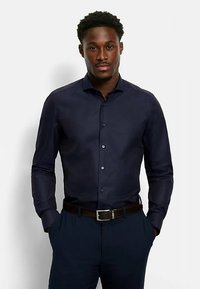 Navy button-up shirt with a textured pattern, long sleeves, and a fitted design, paired with dark pants and a brown belt.