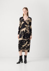Musta ja beige kietaisumekko, jossa on pitkät hihat, kukkakuosi ja midi-pituus. Yhdistetty mustiin nilkkasukkasiin, joissa on paksu korko.