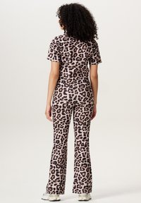 Twee-delig leopardprint outfit gemaakt van zachte stof. Korte mouwen top en flare broek in een roze en zwarte print, met een snug fit.