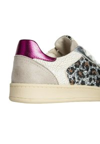 Zapatilla con un suave ante beige texturizado y un lado de estampado de leopardo plateado, que presenta un upper de cuero blanco agrietado y un acento brillante en color púrpura en el talón.