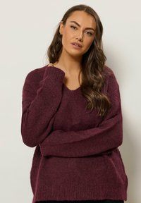 Maglione bordeaux a scollo a V realizzato in un morbido tessuto testurizzato, con maniche lunghe, caratterizzato da una vestibilità rilassata e polsini a costine.