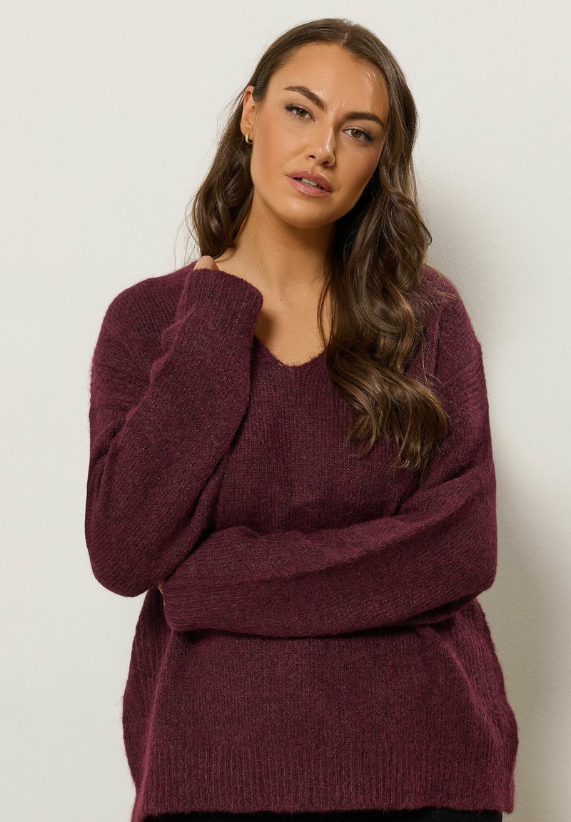Maglione bordeaux a scollo a V realizzato in un morbido tessuto testurizzato, con maniche lunghe, caratterizzato da una vestibilità rilassata e polsini a costine.