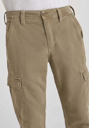 Pantalons cargo en kaki avec poches latérales, passants de ceinture et taille à bouton, portés avec un haut blanc.