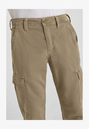 Khaki cargobroek met zijzakken, riemlussen en een knoopsluiting, gedragen met een witte top.