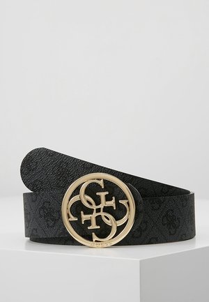 Ceinture noire texturée avec grande boucle ronde dorée présentant les lettres entrelacées G, C, H et le logo GUESS sur une surface blanche.