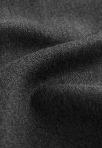 Zwarte stof met een zachte textuur, met een gladde, gelijkmatige oppervlakte en subtiele diepte door gevouwen lagen.