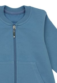 Niebieska kurtka na zamek z prążkowanym kołnierzem, przednimi kieszeniami i srebrnym suwakiem, wykonana z miękkiej dzianiny.