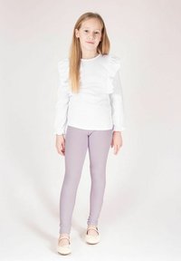 Biała koszula z długim rękawem z falbankami, w połączeniu z jasnofioletowymi legginsami i balerinami. Prosty design, gładka tekstura, dopasowany styl.