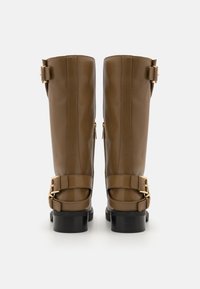 Botine din piele maro, până la genunchi, cu accente din metal auriu, fermoare laterale duble și două curele cu cataramă la gleznă. Tocuri negre, de tip bloc.
