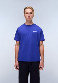 Royal blue bomulds T-shirt med korte ærmer og rund hals, med et lille hvidt logo på venstre brystområde, præsenteret på en neutral baggrund.