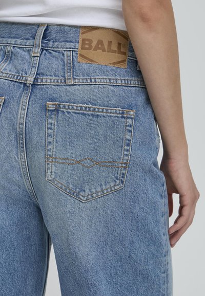 Lichtblauwe denim jeans hebben een patch met het merk "BALL" op de achterkant van de taille, met twee achterzakken en contrasterende stiksels die de zakken omlijnen.