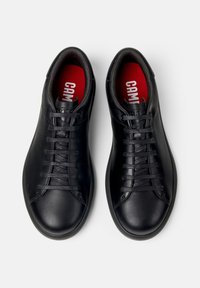 Pair of black leather lace-up sneakers with red insoles displaying white text, viewed from above on a white background.