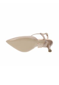 Sandalia de tacón alto beige con puntera puntiaguda, cinta delgada en el tobillo y parte superior de tela texturizada. Suela suave y de color claro con una ligera curvatura.