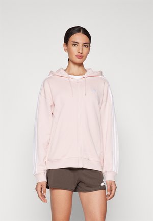 Sudadera con cremallera color rosa, con capucha ajustable y franjas laterales blancas, además de un pequeño logo en el pecho. Tejido suave y corte relajado.