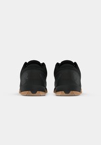 Black athletic shoes with a textured upper, a sleek design, and gum rubber soles. Features a subtle logo on the heel and padded collar.