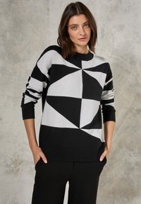 Maglione con motivo geometrico in bianco e nero, maniche lunghe, colletto e polsini a coste, caratterizzato da una vestibilità ampia e un materiale a maglia testurizzato.